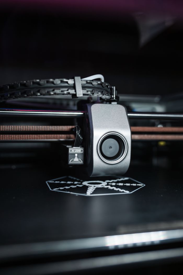 services-02 Detailed close-up view of a modern 3D printer in operation, focusing on the printhead.