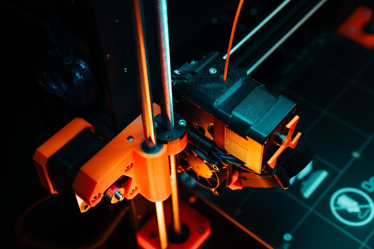 services-01 A colorful close-up of a 3D printer operating, showcasing mechanical precision and technology.