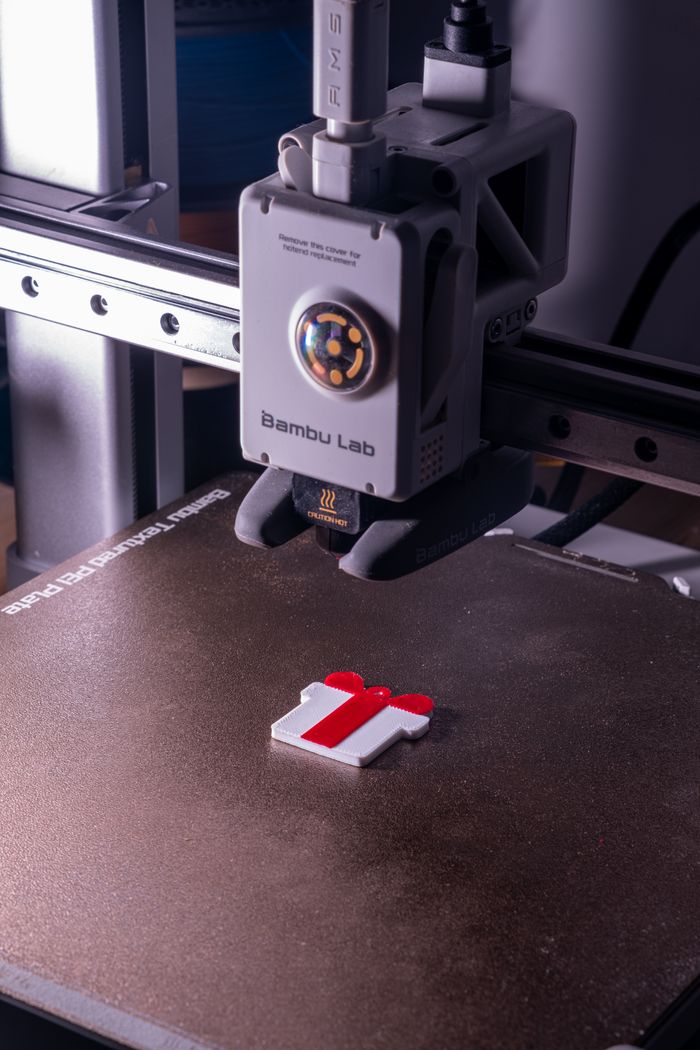 services-04 Close-up of a 3D printer fabricating a red and white object on a build plate.